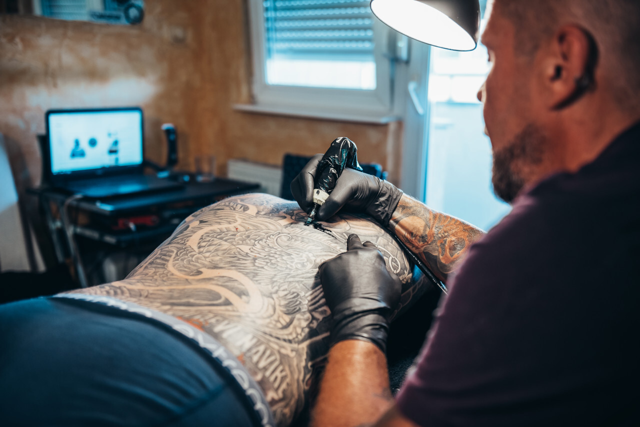 Tattoo artist working on client.